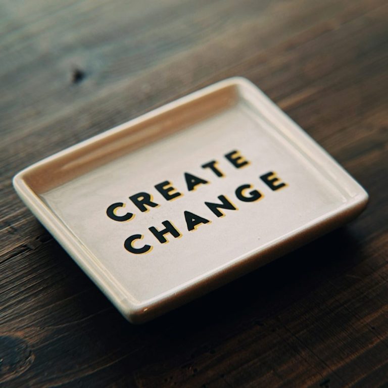 Keramikplatte mit der Aufschrift „CREATE CHANGE“ in goldenen Buchstaben.